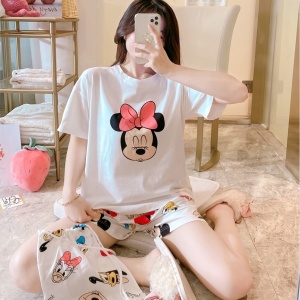 Pigiama estivo in raso con stampa di Minnie Mouse indossato da una donna seduta su un letto in una casa