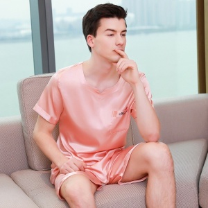 Pigiama in raso rosa per uomo. Si tratta di un set di pigiami che comprende pantaloncini e una maglietta di raso
