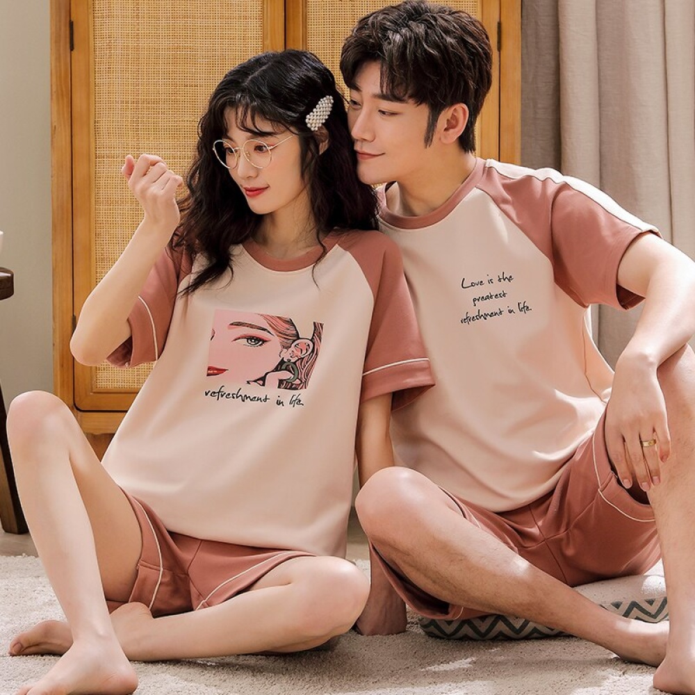 Pigiama in cotone a due pezzi con maglietta bianca e rosa e pantaloncini rosa, indossato da una coppia seduta su un tappeto in una casa