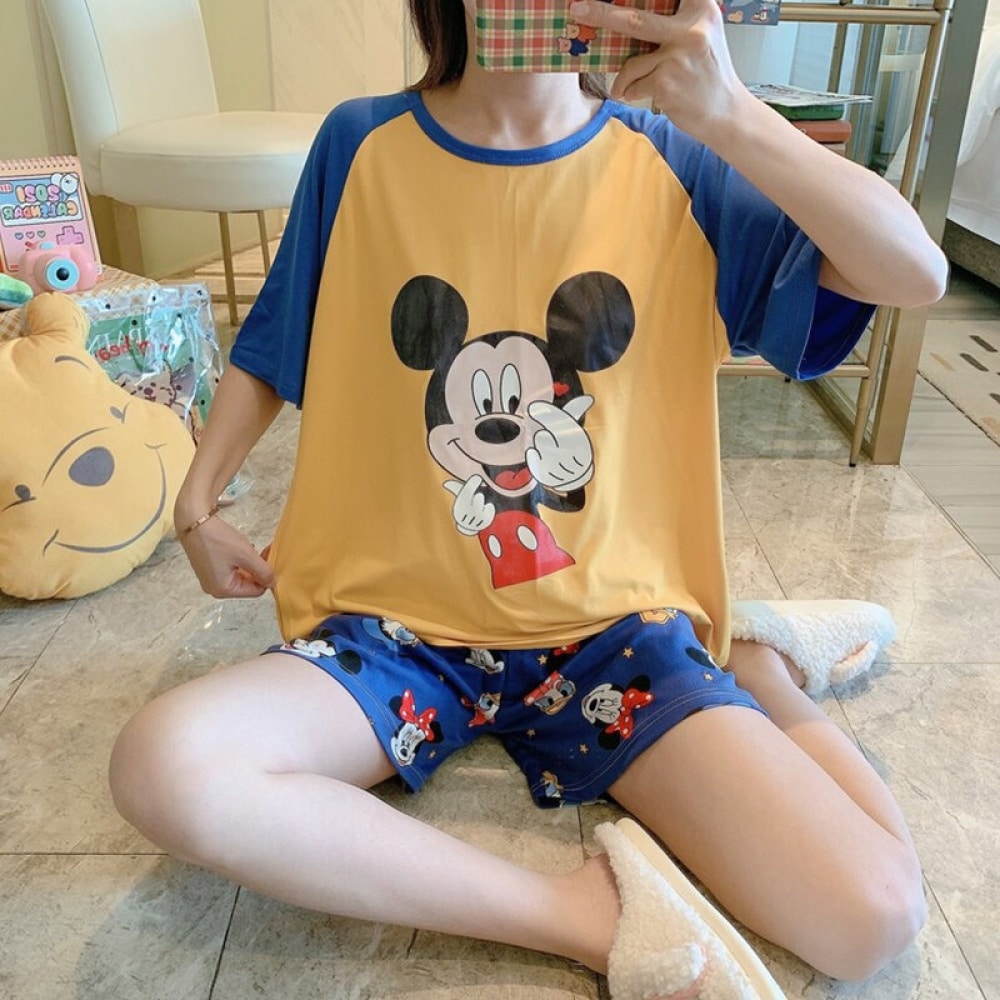 Maglietta e pantaloncini a due pezzi con motivo Mickey indossati da una donna seduta che sta scattando una foto in una casa
