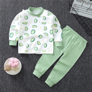 Pigiama da bambino in cotone avocado con pantaloni verdi a tinta unita alla moda su un tappeto in una casa