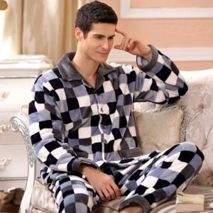 Pigiama da uomo in pile a scacchi, indossato da un uomo seduto su un divano in una casa