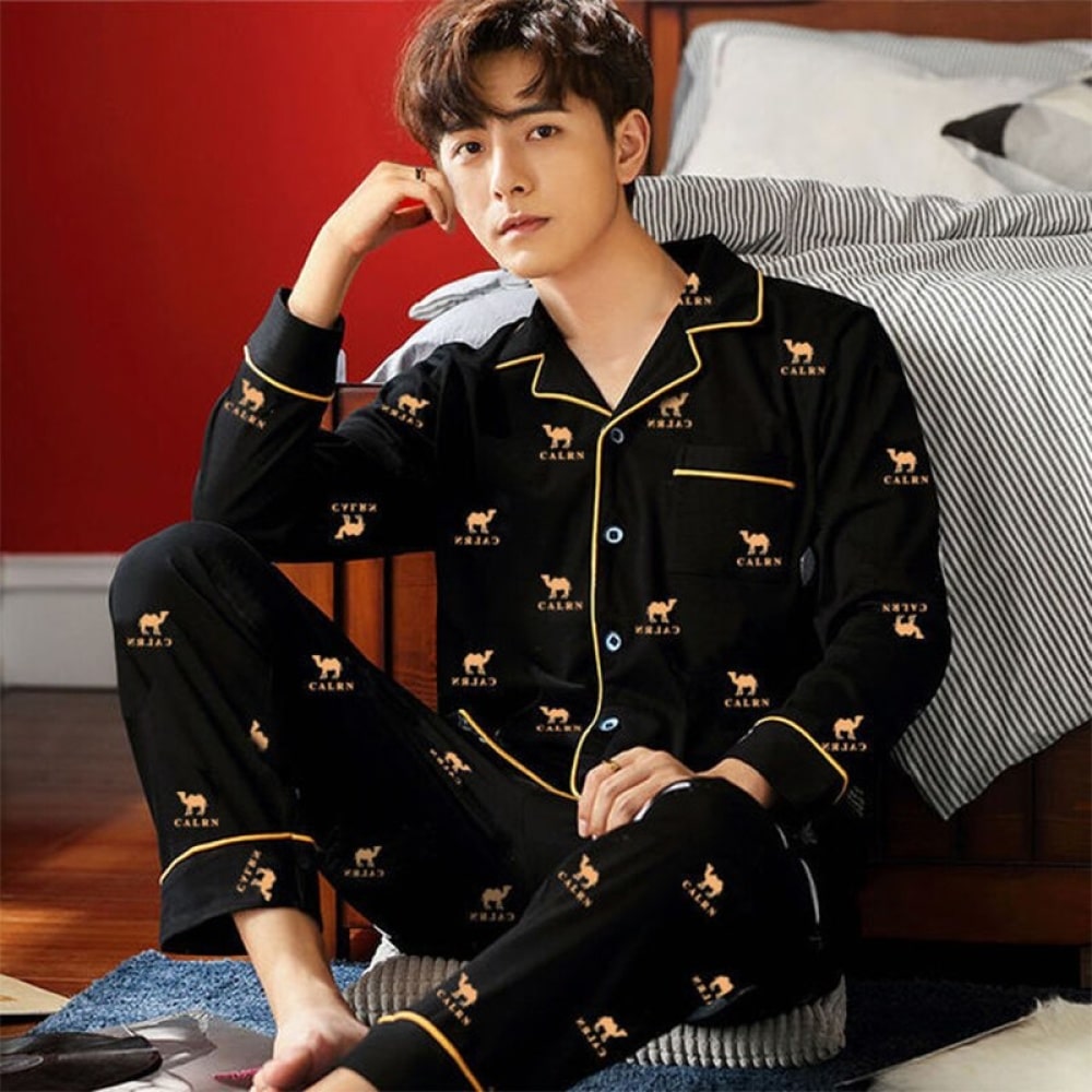 Un pigiama di cammello di cotone indossato da un uomo seduto su un tappeto davanti a un letto in una casa