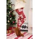 Leggings con stampa natalizia bianca e rossa per donna, indossati da una donna in una casa