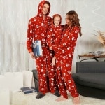 Pigiama natalizio con cappuccio per tutta la famiglia, indossato da una famiglia davanti a un divano in una casa