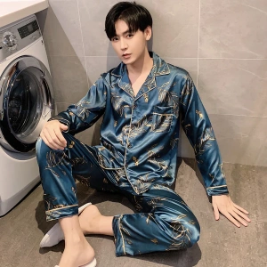 Pigiama blu satinato da uomo indossato da un uomo seduto davanti a una lavatrice in una casa