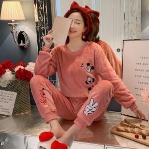 Pigiama rosa Mickey da donna indossato da una donna con una fascia rossa in una casa alla moda