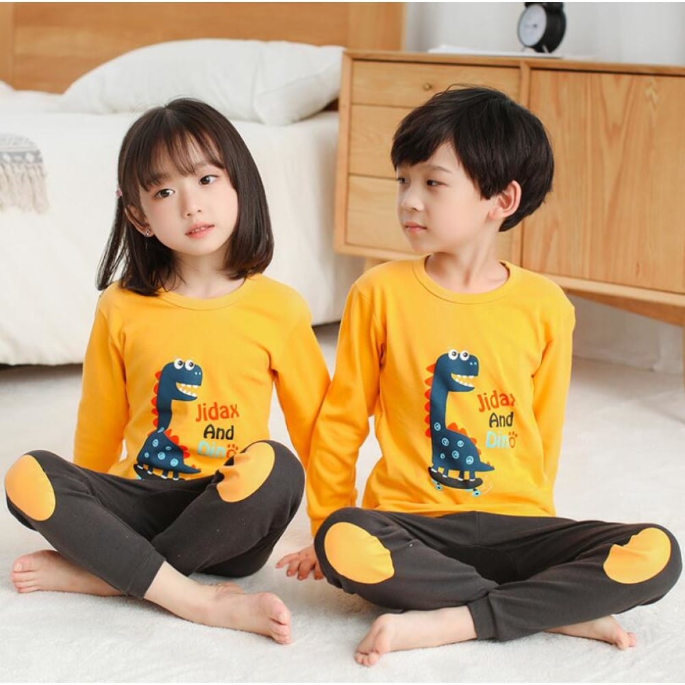 Pigiama per bambini con maglia gialla da dinosauro e pantaloni marroni con due bambini che indossano il pigiama