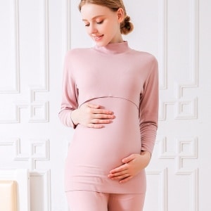 Un pigiama premaman a due pezzi in cotone rosa viene indossato da una donna bionda incinta