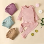 Pigiama semplice in cotone per bambine, con diversi pigiami piegati e uno sfondo beige