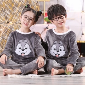 Pigiama di flanella Panpan rabbit per bambini indossato da un bambino e una bambina seduti su un tappeto davanti a un comodino in una casa