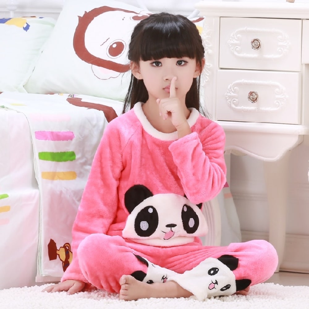 Pigiama rosa a due pezzi con panda per una bambina, indossato da una bambina seduta su un tappeto davanti a un letto in una casa