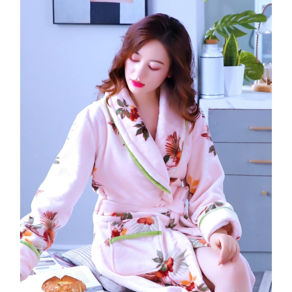 Pigiama da donna in pile con stampa floreale indossato da una donna seduta su un letto in una casa
