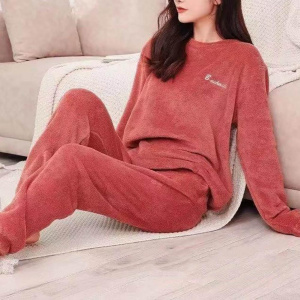 giovane donna che indossa un pigiama rosso pilou pilou, è seduta su un plaid vicino a un divano sul pavimento